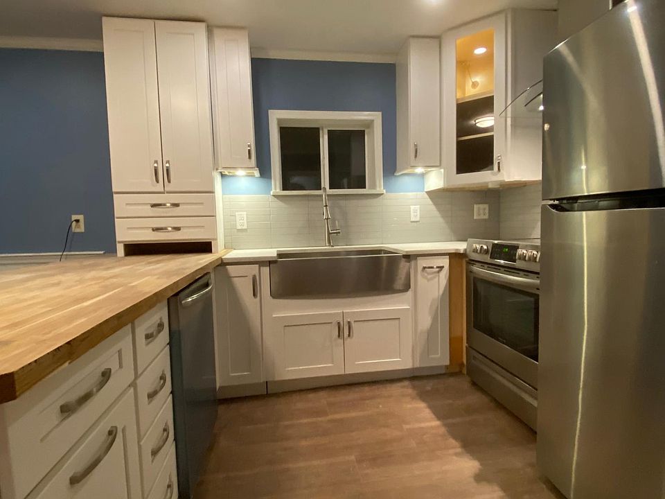 Kitchen with farm sink, new floors, recessed lighting, and custom tile.