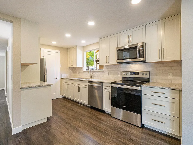 Kitchen with hard surface counter tops, shaker cabinets and stainless appliances