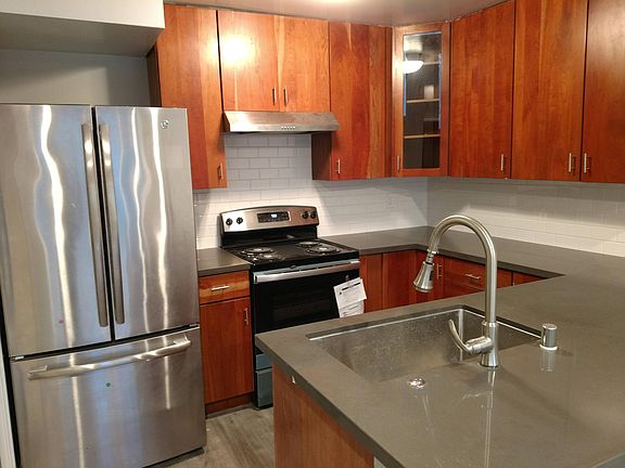 Remodeled kitchen with cherry hardwood cabinetry and new appliances, new quartz countertop and tile backsplash.