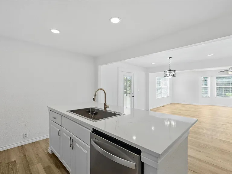 Kitchen with dishwasher, a sink, light wood-type flooring, open floor plan, and a center island with sink
