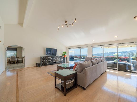 Very large open living/dining room with cathedral ceiling, hardwood floor and sliding glass doors with stunning views
