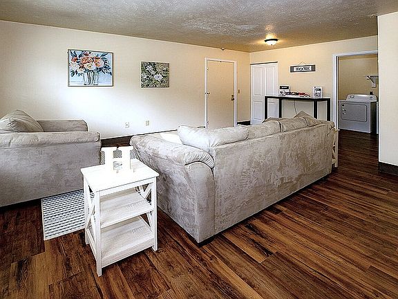 Inviting living room with plush beige sofas, stylish art decor, and elegant wooden flooring.