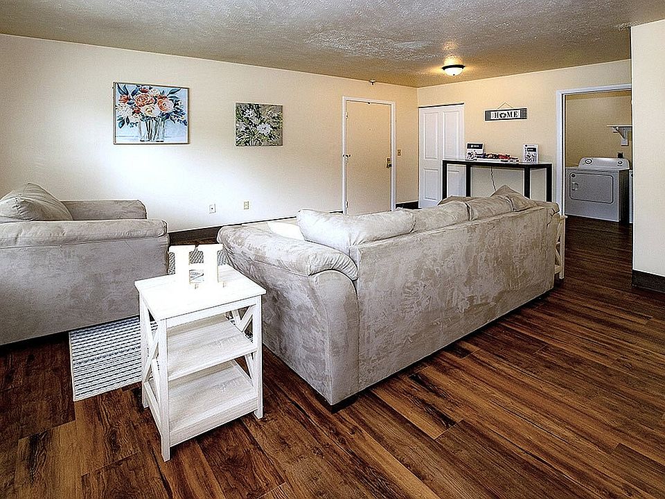 Inviting living room with plush beige sofas, stylish art decor, and elegant wooden flooring.