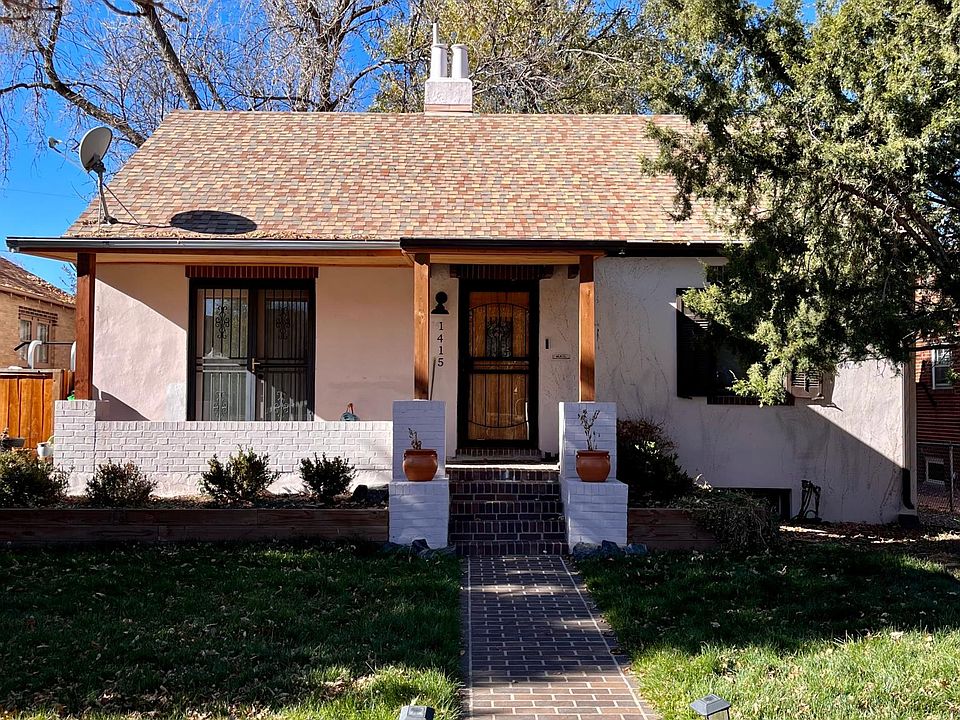 Front of house featuring lawn with irrigation, covered porch, French doors, and evergreen trees.