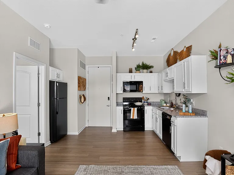 Modern open kitchen with elegant white cabinets, sleek black appliances, and stylish decor, featuring a cozy seating area for a welcoming atmosphere.