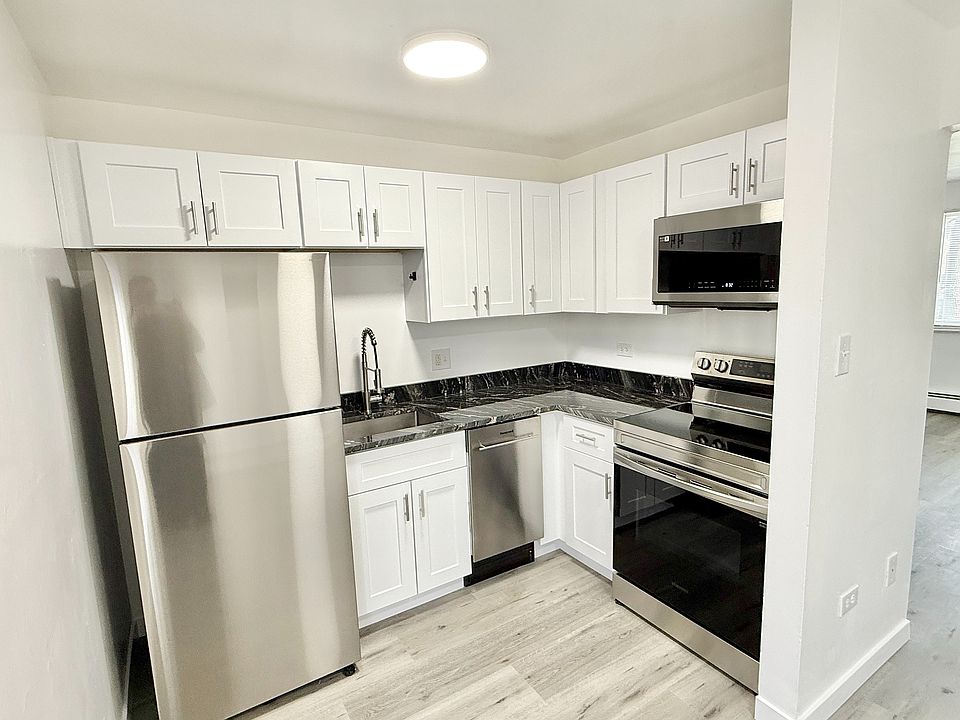 Modern kitchen with sleek stainless steel appliances, elegant white cabinetry, and a stylish black marble countertop, blending seamlessly into an open, airy layout.