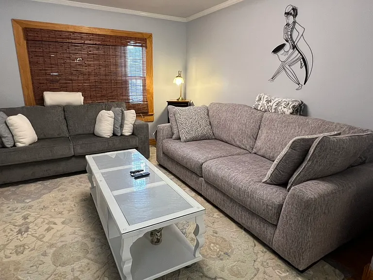 Beautifully furnished living room. Clean lines, calming blue colors, large glass covered coffee table, plush king size blankets for curling up in front of the TV.