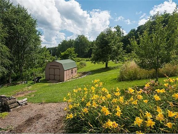 Storage building that stays, beautifully landscaped and planned slightly sloping yard with lots of shrubs, trees, flowers etc.