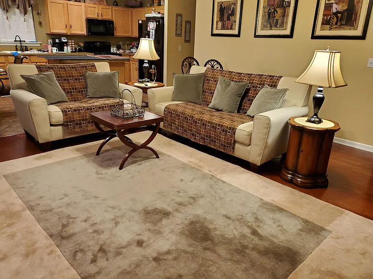 Huge furnished family room with couch, loveseat, end tables, lamps, himalayan wool area rug, 70" Sharp smart TV.