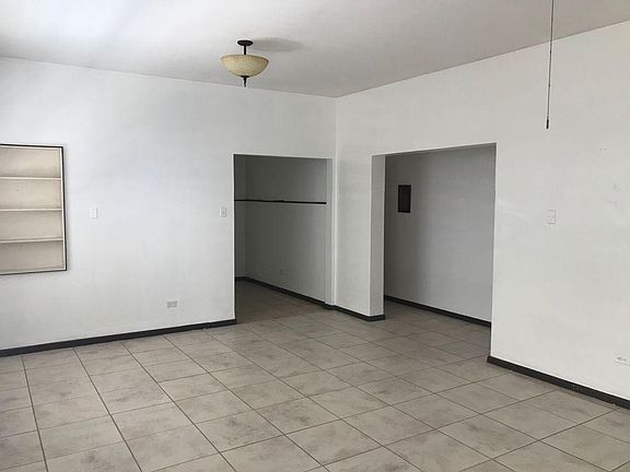 Ten feet tall ceilings through the house. Shown here living/dining space with incrusted bookcase on the wall. The right hall leads to two of the bedrooms. At the end to the left is the kitchen with space for a small breakfast table.