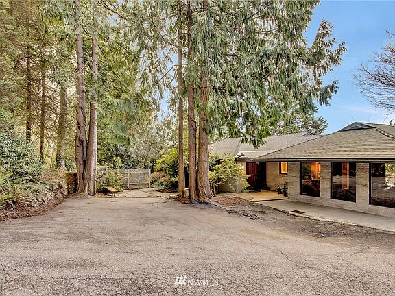 Front of home shows first driveway with lots of parking. Front courtyard in the distance with brick barbeque.