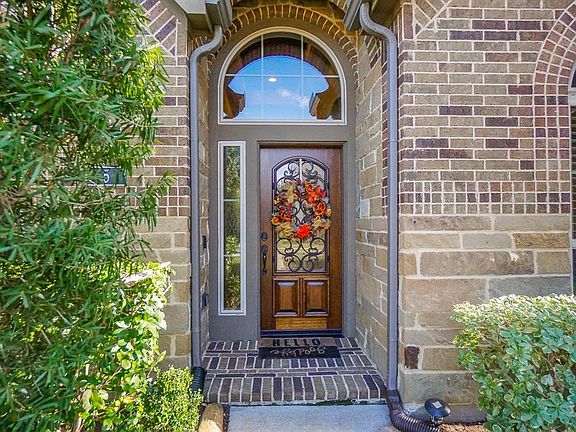 Brick paver front porch and beautiful leaded glass front door with wrought iron decor