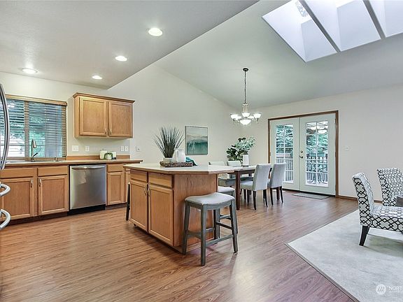View from entry hall to your kitchen and dining area. Note the cathedral ceilings, generous skylights and French Doors leadingto your deck. Open concept living to your family room on the right. What a place to gather! >