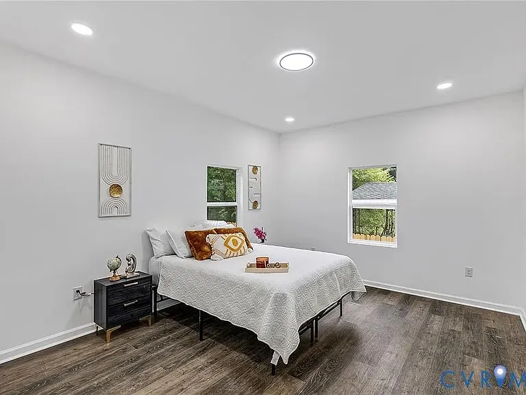 Spacious bedroom with recessed lighting, wood-style floors, and two windows for natural light and fresh-air ventilation.