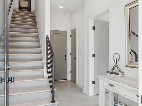 Clean lines, tall ceilings, and a stylish stairway welcome you inside_an entry that feels both open and elevated, with access to a private suite and bathroom on the first floor.