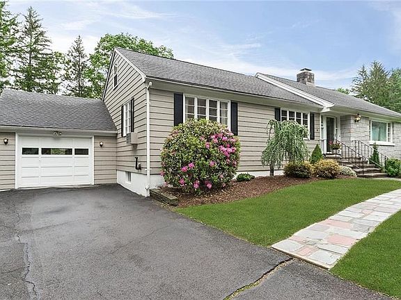 Exterior side front picture of 12 Woodside with flagstone front walk. One car garage with access to the basement. Additional parking space on the side of the garage.