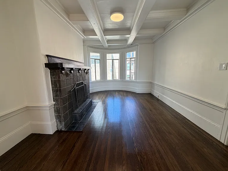 Living room with bay windows and fireplace. The living room door closes from hallway and has pocket doors to separate it from the dining room.