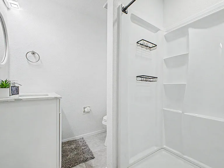 Clean bathroom with a tub/shower combo, built-in shelving, and a vanity with mirror for everyday convenience.
