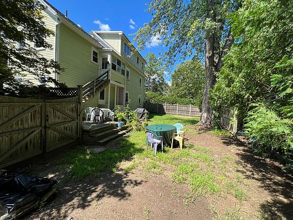 Fenced-in backyard with deck and grill.