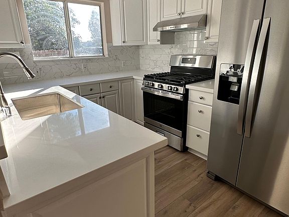 Kitchen with new stainless steel range and range hood, marble backsplash
