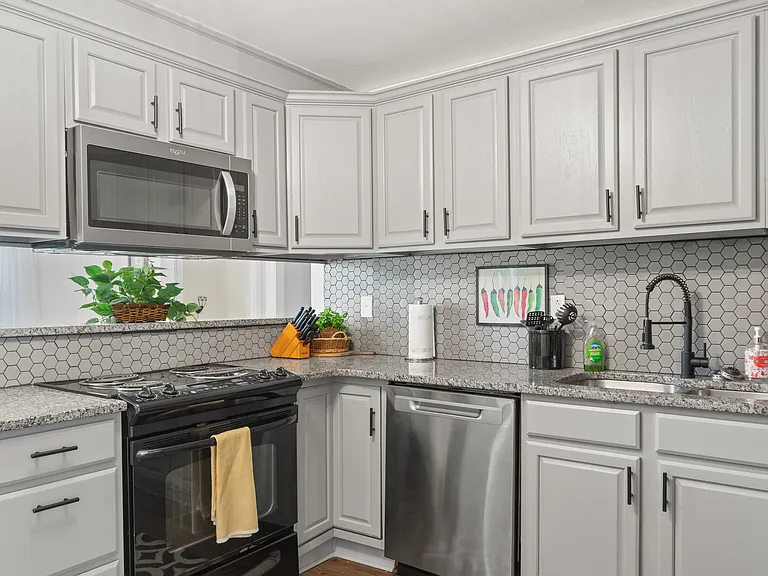 Fully stocked kitchen with pots, dishes, glasses, and silverware.