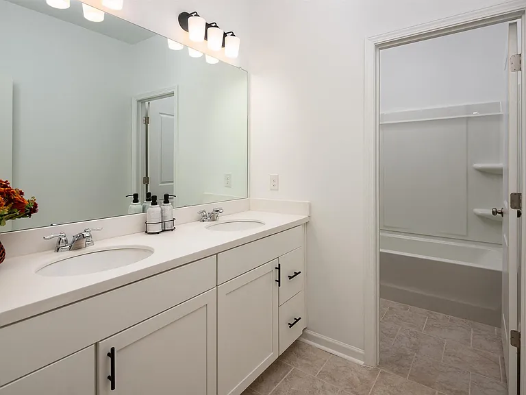 Alternate view of the third bathroom showcasing a double vanity and a tub-shower combination.
