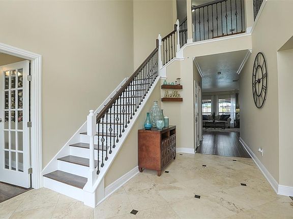 A grand entryway greets you at the door! Travertine and new iron staircase spindles lend a sleek touch to the neutral tones of the two story foyer.