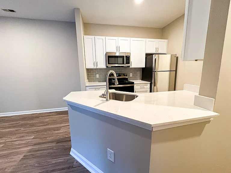 Sleek kitchen finishes with white granite countertops, white cabinets, and stainless steel appliances.