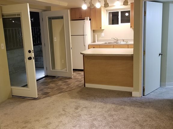 View of entry, kitchen, bathroom, living area from bedroom door. Reserved parking space (that could be used as a patio) is right outside the kitchen window.