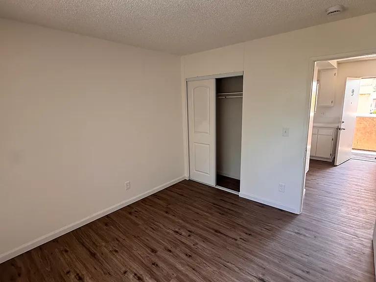 Bedroom with closet and wood flooring.