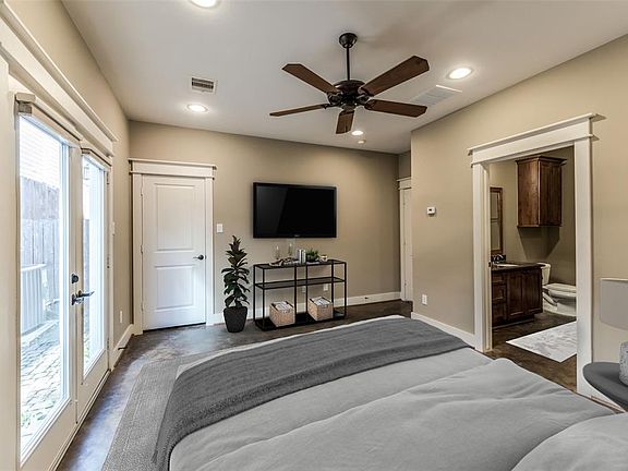 Virtually staged large primary bedroom with easy to maintain concrete floors. Double doors lead to the patio area providing great natural lighting. Primary bath on the right. High ceilings with recessed lighting and ceiling fan.
