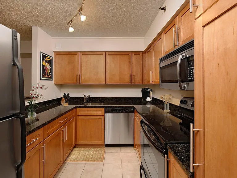 Kitchen with granite countertops, oak cabinetry, stainless steel appliances and tile flooring