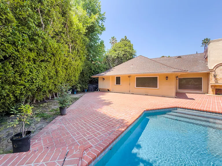 Expansive brick pool deck with tall privacy hedges offers a secluded escape at this Beverly Hills luxury rental, 1094 Garden Lane, 90210.