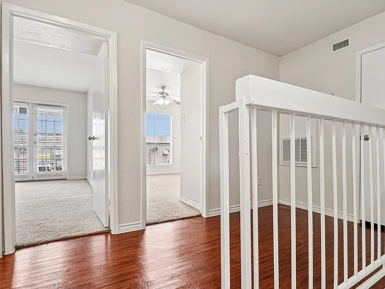 Inviting modern hallway with warm wood-style floors leading to bright bedrooms, featuring white walls and ample natural light. Inviting modern hallway with warm wood-style floors leading to bright bedrooms, featuring white walls and ample natural light.
