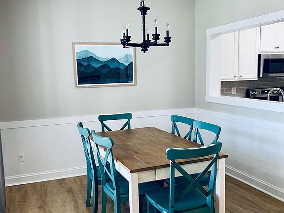 Comfortable farmhouse dining with dimmable rustic chandelier. Open concept into kitchen.