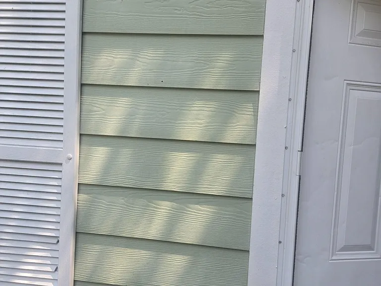 Covered porch entry with a secure exterior door and adjacent shuttered window for easy access and ventilation.