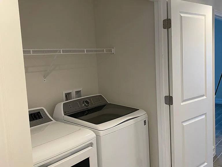 Laundry room with shelf for easy storage of cleaning supplies.