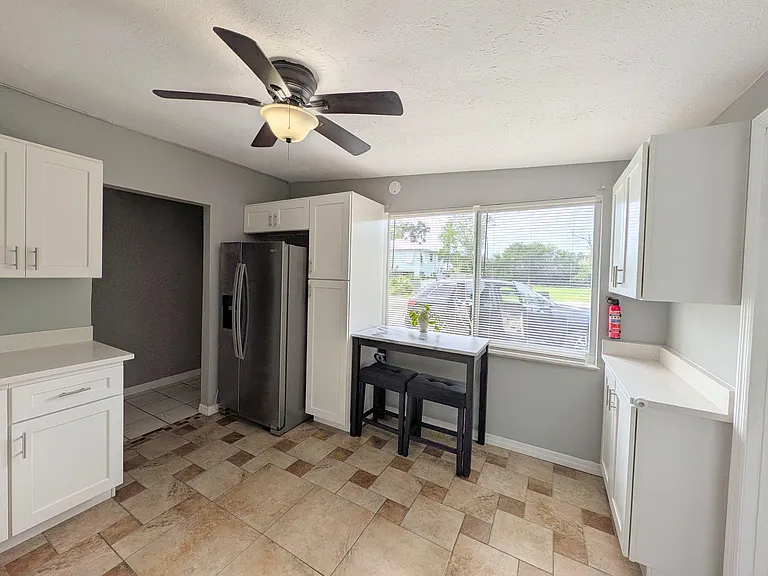 Updated kitchen with ample cabinet storage, full-size fridge, and a dine-in nook by a large window for everyday meals.