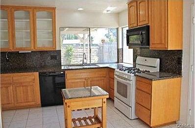 Remodeled kitchen has granite counters and attractive display ca