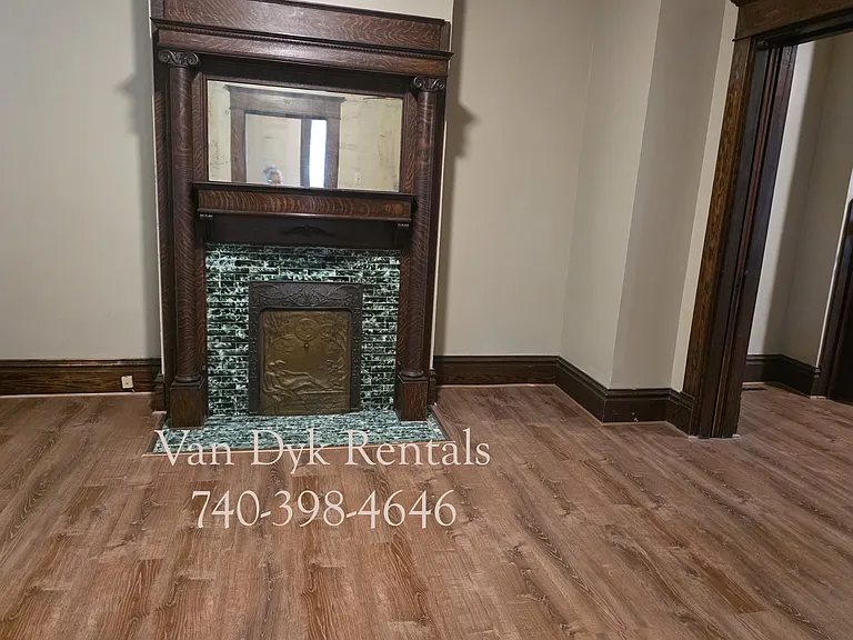 Decorative fireplace and pocket doors in living room, looking into dining room to the right.