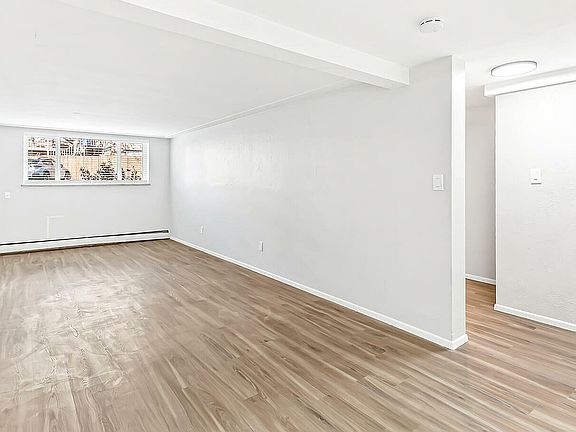 Bright and spacious living area with elegant hardwood flooring and large window offering ample natural light.