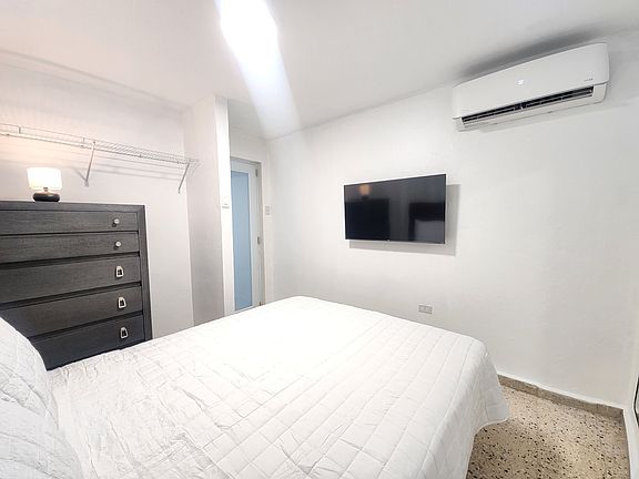 Master bedroom with queen size bed, 43" TV and mini split ac unit.