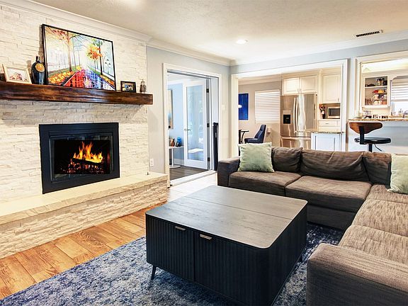 Spacious living room boasts a decorative gas fireplace with a beautiful wood mantel and raised extended hearth, recessed lighting, and ceramic wood-look tile floors. The open layout provides views of the kitchen, sunroom and dining areas.Love the stacked stone fireplace and additional seating.