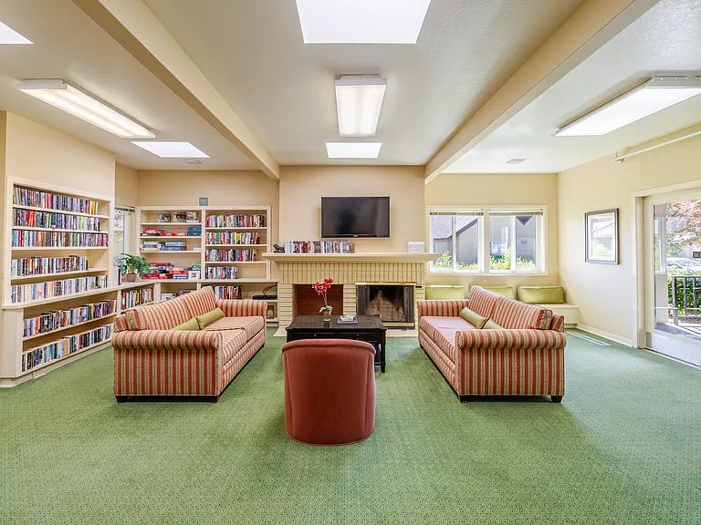 Cozy resident lounge with built-in bookshelves, inviting seating, and a warm fireplace for relaxation.