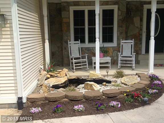 Front porch and gardens featuring pond