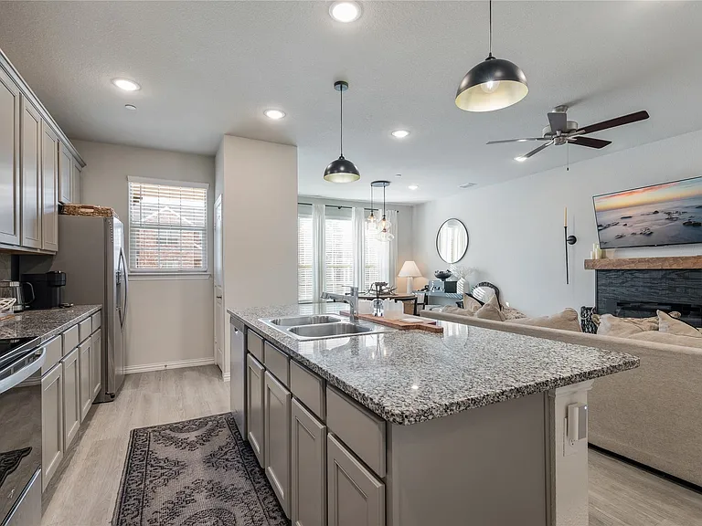Kitchen featuring a central island with dual sinks, granite countertops, stainless steel appliances, light gray cabinetry, and recessed lighting