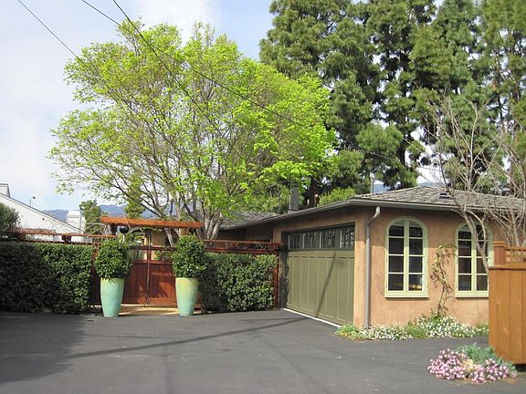 driveway, garage door, arched windows into garage/play room, gated front entry and arbor