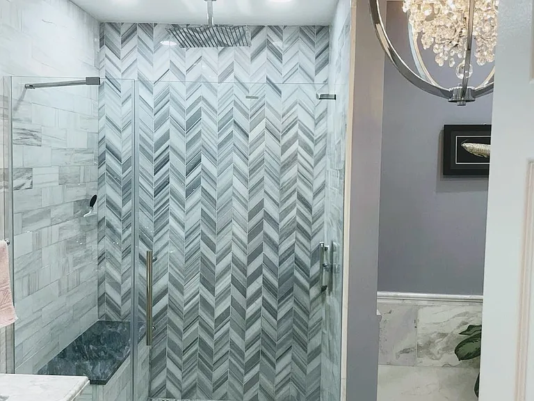 Master bath features a rain shower head, marble bench, hand shower, dual sink vanity, and ample storage space.