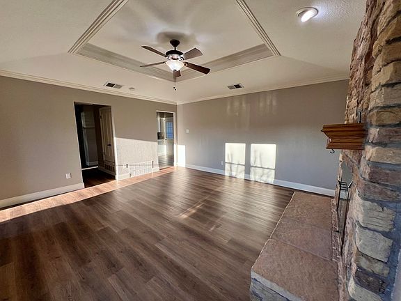 This living room has a raised ceiling with a ceiling fan, new LVP floors installed January 2025, and crown molding. It's a great space for entertaining or just relaxing.