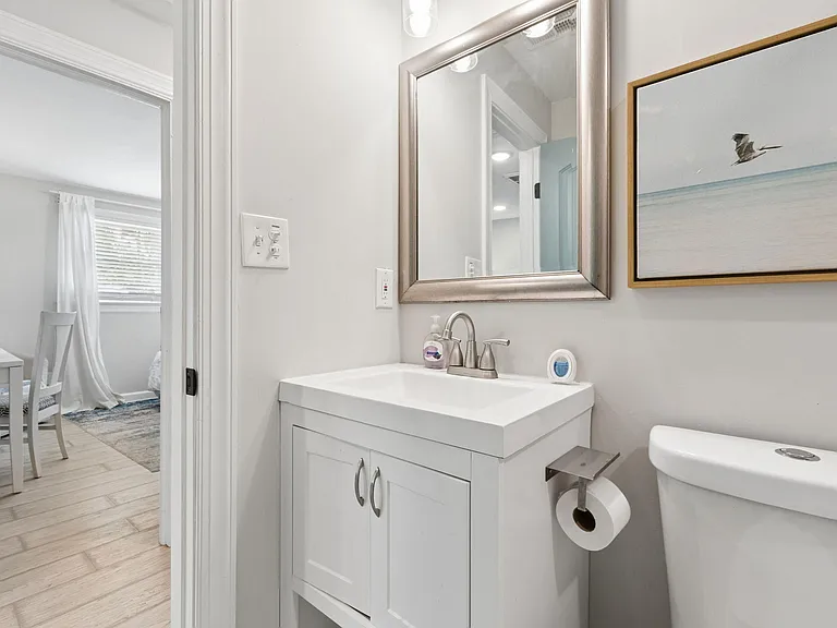 Clean bathroom vanity area with a framed mirror, under-sink storage, and a well-placed sink and toilet for daily use.